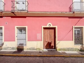 A building with a red facade, a wooden door, and barred windows. - GuestReady - San Fernando II (San Fernando)