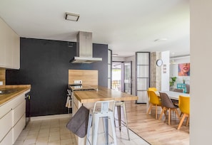 A modern kitchen with a wooden countertop, a built-in stove, and a stainless steel range hood. - GuestReady - Valdelagrana Gus (El Puerto de Santa María)