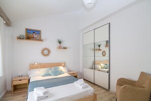 A bedroom with a bed, bedside tables, a mirror, and a chair. - GuestReady - Valdelagrana Gus (El Puerto de Santa María)