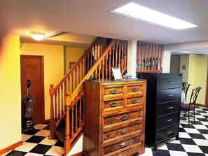 A staircase with wooden balusters, a wooden chest of drawers, a black filing cabinet, and a checkered floor.