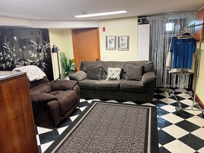 Una habitación con un sofá, una silla, un tapete estampado y suelo a cuadros.