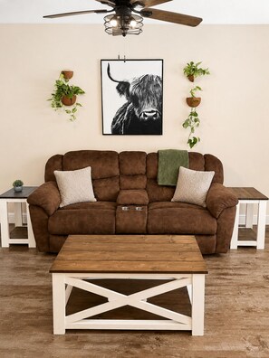 A brown sofa with two pillows, a wooden coffee table, and a ceiling fan.