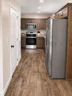 A kitchen with wooden cabinets, a stainless steel refrigerator, an oven, and a microwave.