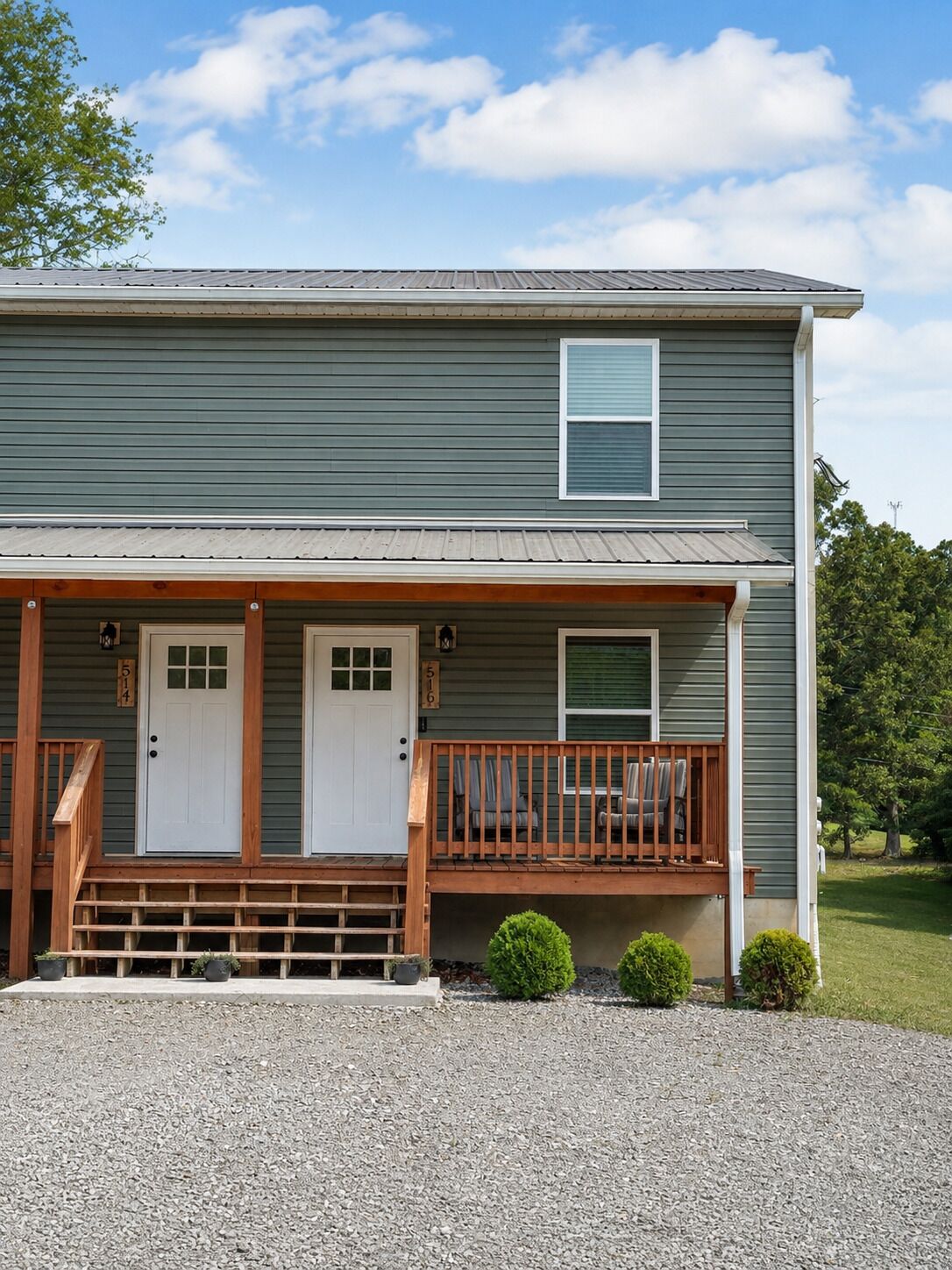 A two-story house with a front porch, a garage door, and a small front yard.