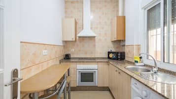 Una cocina compacta con horno integrado, microondas, lavaplatos y lavadora.