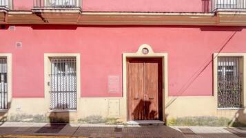 Un edificio con fachada roja, puerta de madera y ventanas con rejas.