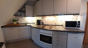 A compact kitchen with a microwave, stove, sink, and cabinets.