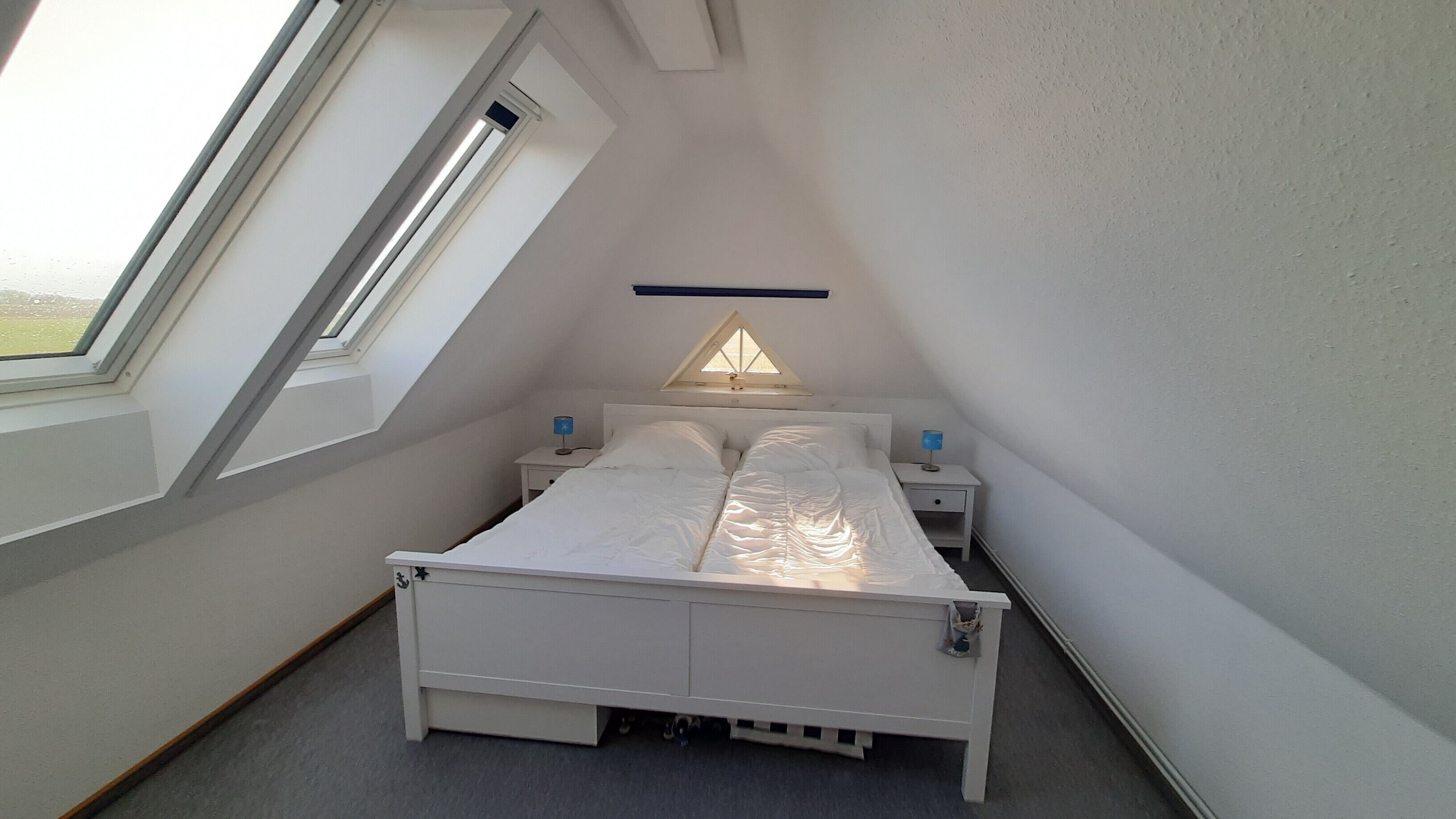 Ein Schlafzimmer mit einem Bett, zwei Nachttischen, einem Oberlicht und einem Fenster.