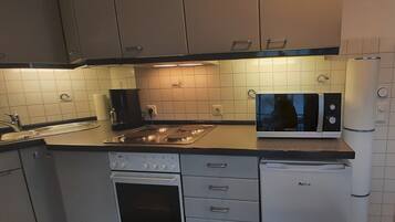Uma cozinha compacta com forno embutido, micro-ondas e frigorífico.