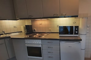Eine kompakte Küche mit Einbauofen, Mikrowelle und Kühlschrank.