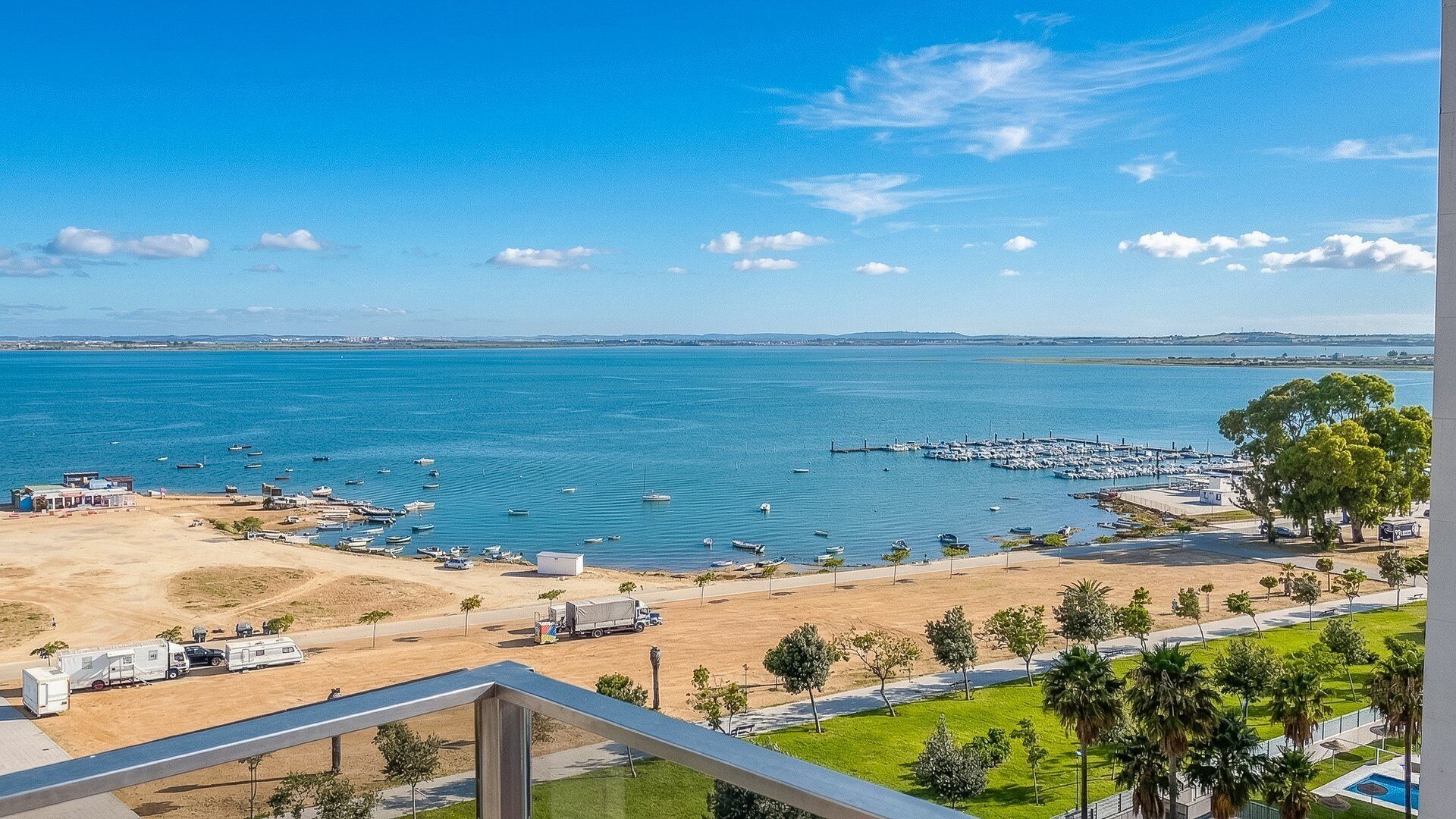 Een uitzicht op de kust met een jachthaven, boten en een heldere lucht.