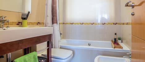 A bathroom with a sink, toilet, bidet, and bathtub.