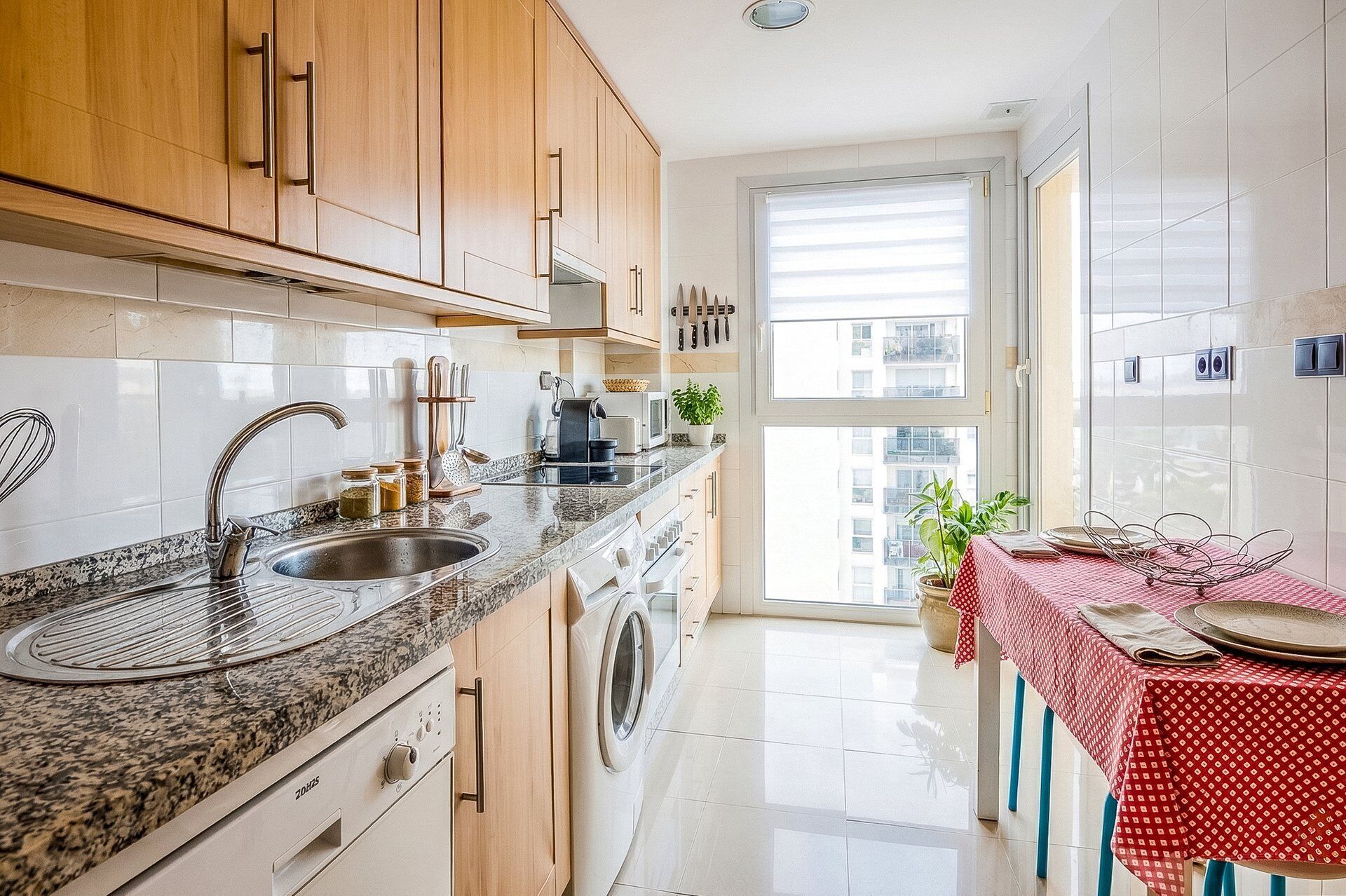 A modern kitchen with a granite countertop, stainless steel sink, and wooden cabinets.