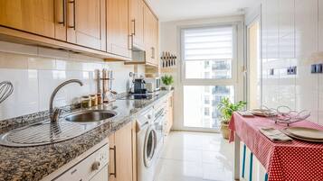 A modern kitchen with a granite countertop, stainless steel sink, and wooden cabinets.