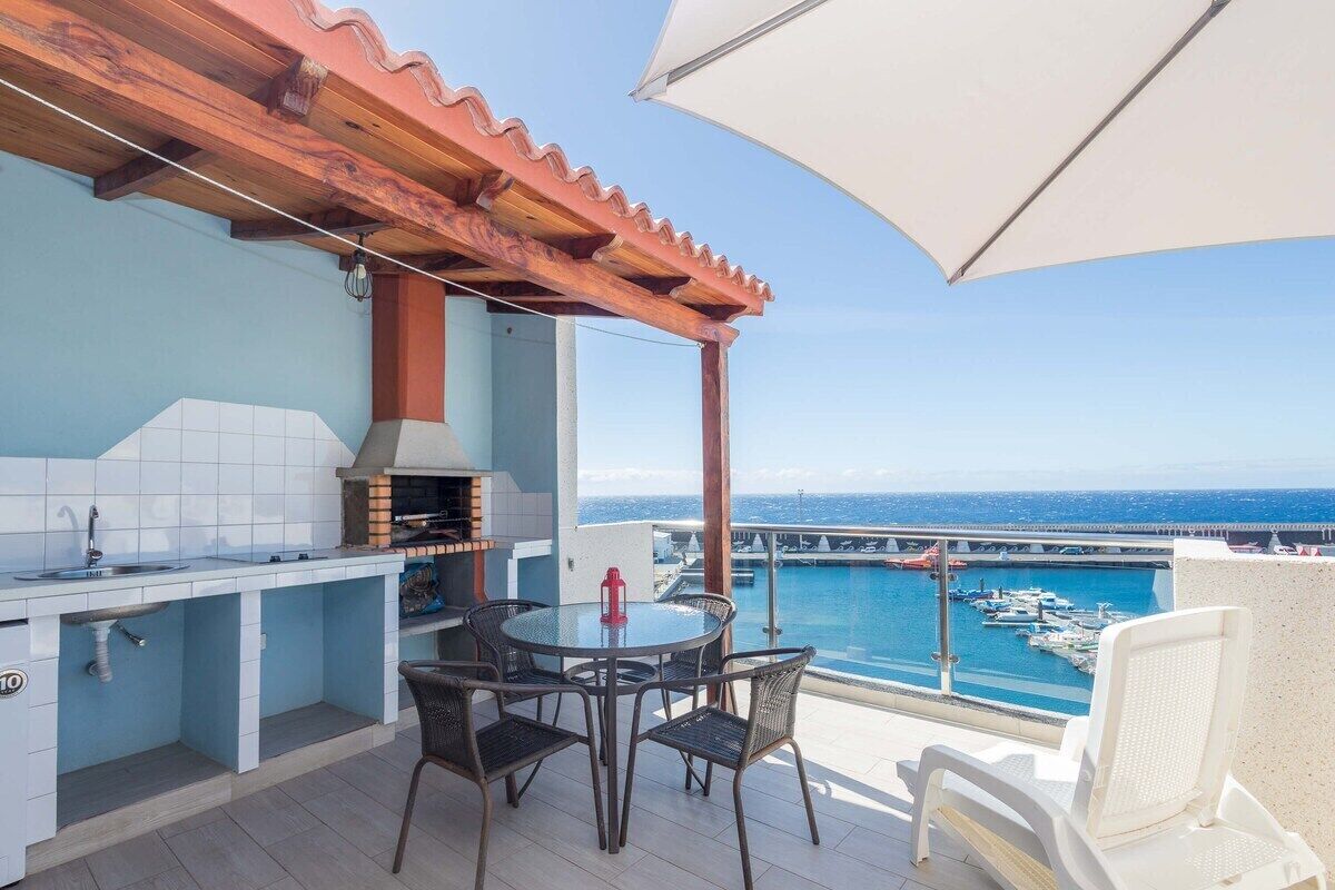 An outdoor kitchen with a view of the sea and boats.