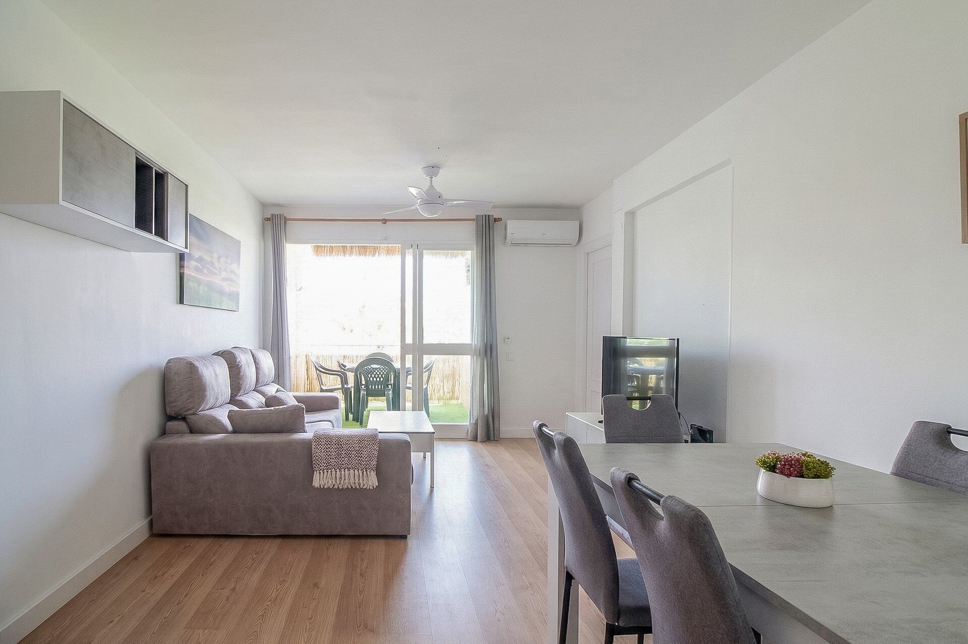Una sala de estar moderna con un sofá, una mesa de comedor, sillas y un televisor.