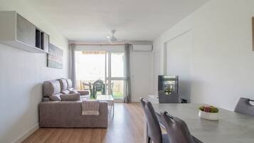Una sala de estar moderna con un sofá, una mesa de comedor, sillas y un televisor.