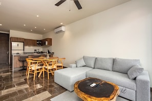 A modern living room with a grey sofa, wooden dining table, and chairs. - 3BR Tulum Retreat with Private Terrace (Tulum)
