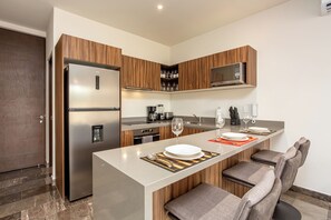 Una cocina moderna con refrigerador, microondas y cafetera integrados.