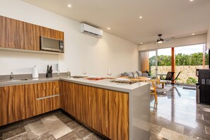 Una cocina moderna con armarios de madera, microondas integrado y comedor con pared de piedra.