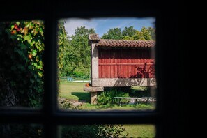 A red wooden structure with a tiled roof, surrounded by greenery and a clear sky. - Casa de Requeixo - 4-bedroom vacation home with a shared pool (Povoa De Lanhoso)