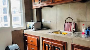 A kitchen with wooden cabinets, a microwave, and a sink.
