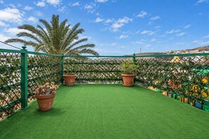 A rooftop terrace with artificial grass, potted plants, and a green fence. - GuestReady - Historic House Mountain Views (Valverde)