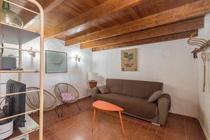A cozy living area with a sofa, a small orange table, wicker chairs, a map on the wall, and a coffee machine. - GuestReady - Historic House Mountain Views (Valverde)