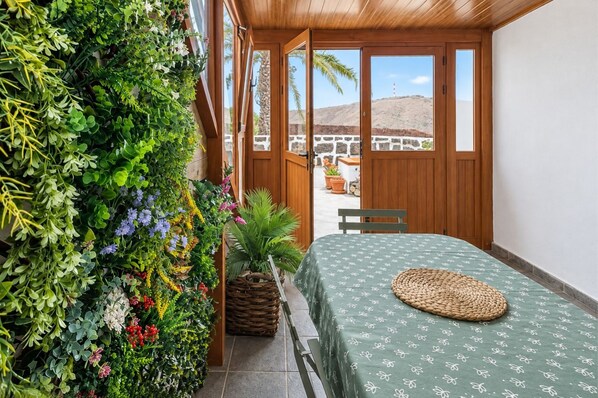 Een kamer met een bed, een bankje, een wandplant en uitzicht op een heuvel.