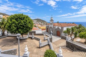A courtyard with a church, stone walls, and a view of the sea. - GuestReady - Historic House Mountain Views (Valverde)
