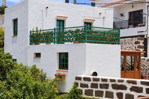 A white building with a green balcony, a stone wall, and a wooden door. - GuestReady - Historic House Mountain Views (Valverde)