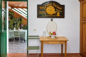A room with a green door, a table with a bowl of fruit, a wall-mounted mirror, and a sign reading 'The Finest Tea Shop.' - GuestReady - Historic House Mountain Views (Valverde)