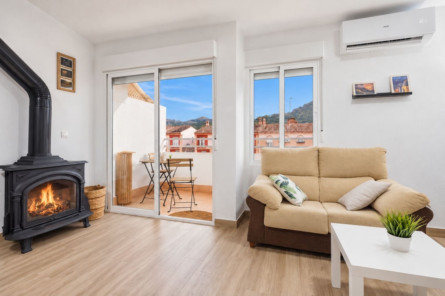 Un salon avec une cheminée, un canapé, une table avec une plante et un balcon avec vue.