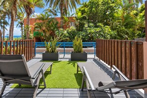 An outdoor seating area with two lounge chairs and a small patch of artificial grass, surrounded by a wooden fence and potted plants. - GuestReady - Beach Escape by Cancajos (Breña Baja)