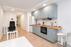 Una cocina moderna con armarios azul claro, encimera de madera y horno empotrado.