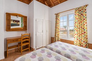 A bedroom with a bed, a desk, a wardrobe, and a window with curtains. - GuestReady - Colon I 11 2 pax (Los Quemados)