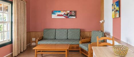 Ein gemütliches Wohnzimmer mit Holzboden, einer Sofagarnitur, einem Couchtisch und einem Bild an der Wand.