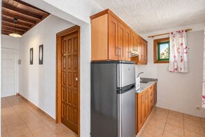 Une cuisine avec des meubles en bois, un réfrigérateur en acier inoxydable et une fenêtre avec un rideau.