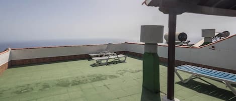 Una terraza en la azotea con vista despejada al horizonte, un área de estar techada y un depósito de agua.