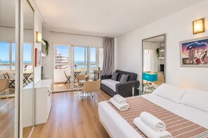 A modern hotel room with a balcony, a sofa, a dining area, and a large mirror. - GuestReady - Las Dalias Torremolinos Comfort (Torremolinos)