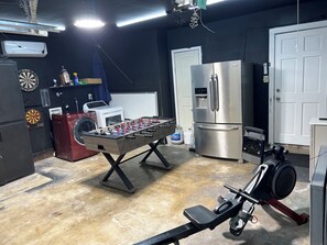 Ein Zimmer mit Kicker, Waschmaschine, Kühlschrank und Laufband.