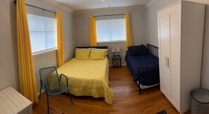 Ein Schlafzimmer mit einem Bett, einem Sessel, einem Nachttisch mit Lampen und einem Kleiderschrank.