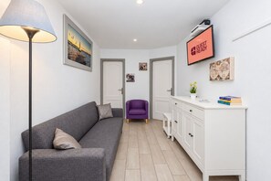 A modern living room with a grey sofa, a purple armchair, a white cabinet, and a floor lamp. - GuestReady - Beachfront Apartment Marina Views (La Restinga)