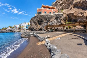 Un hotel a la costa amb un penya-segada rocosa, una passera de fusta i vista al mar.