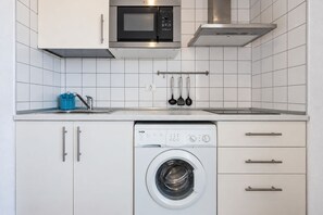 A compact kitchen with a microwave, oven, and built-in washing machine. - GuestReady - Beachfront Apartment Marina Views (La Restinga)