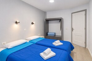 A hotel room with two beds, a wardrobe, a mirror, and a door. - GuestReady - Beachfront Apartment Marina Views (La Restinga)