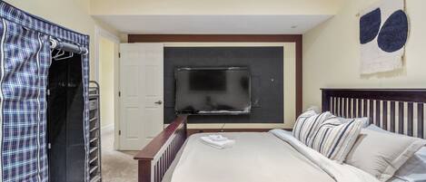 Un dormitorio con cama, televisión, armario y una obra de arte en la pared.