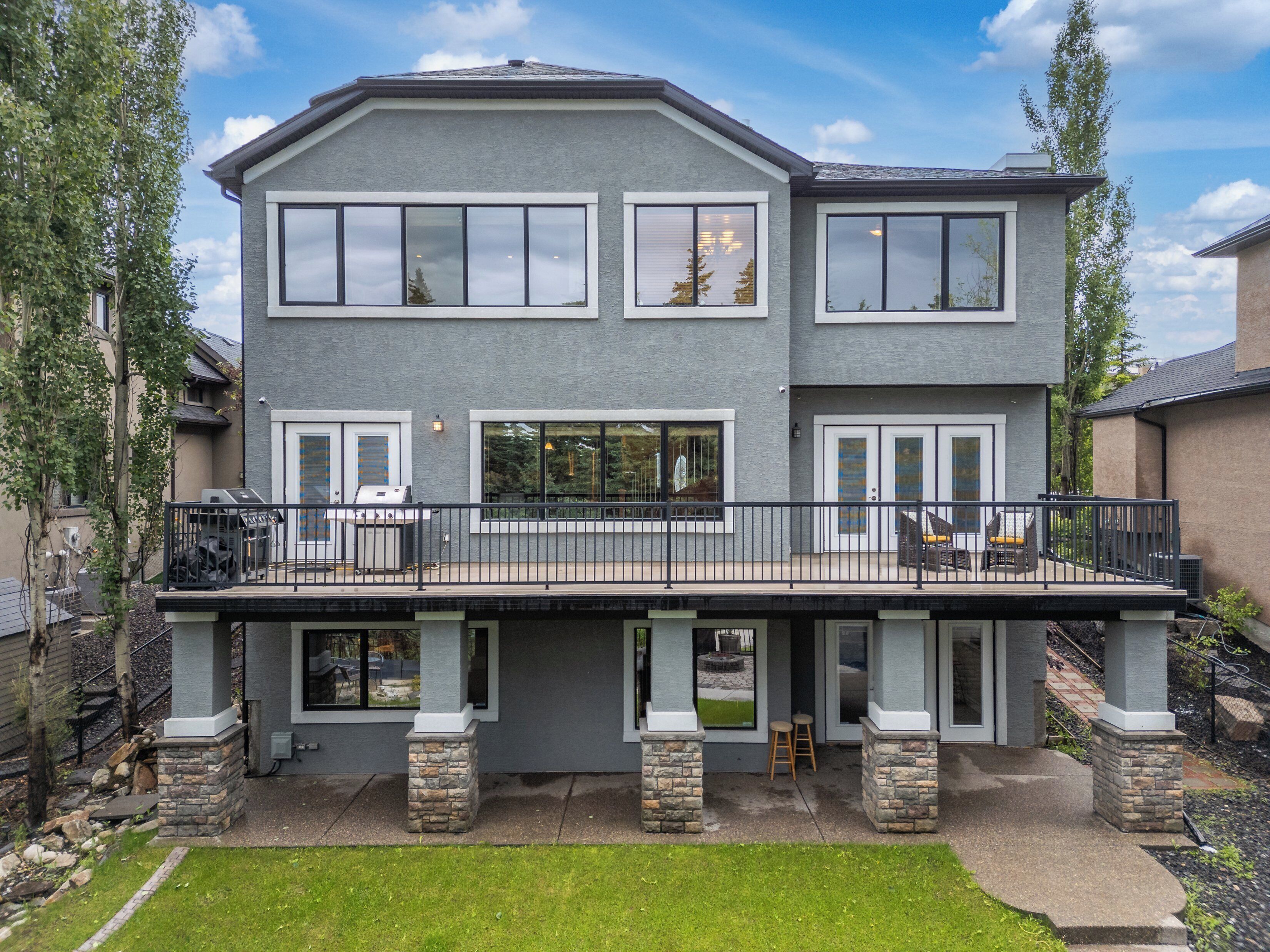 A two-story house with a balcony, stone pillars, and a well-maintained lawn.