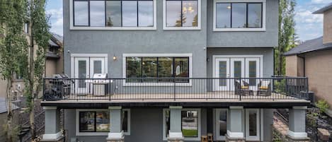 A two-story house with a balcony, stone pillars, and a well-maintained lawn.