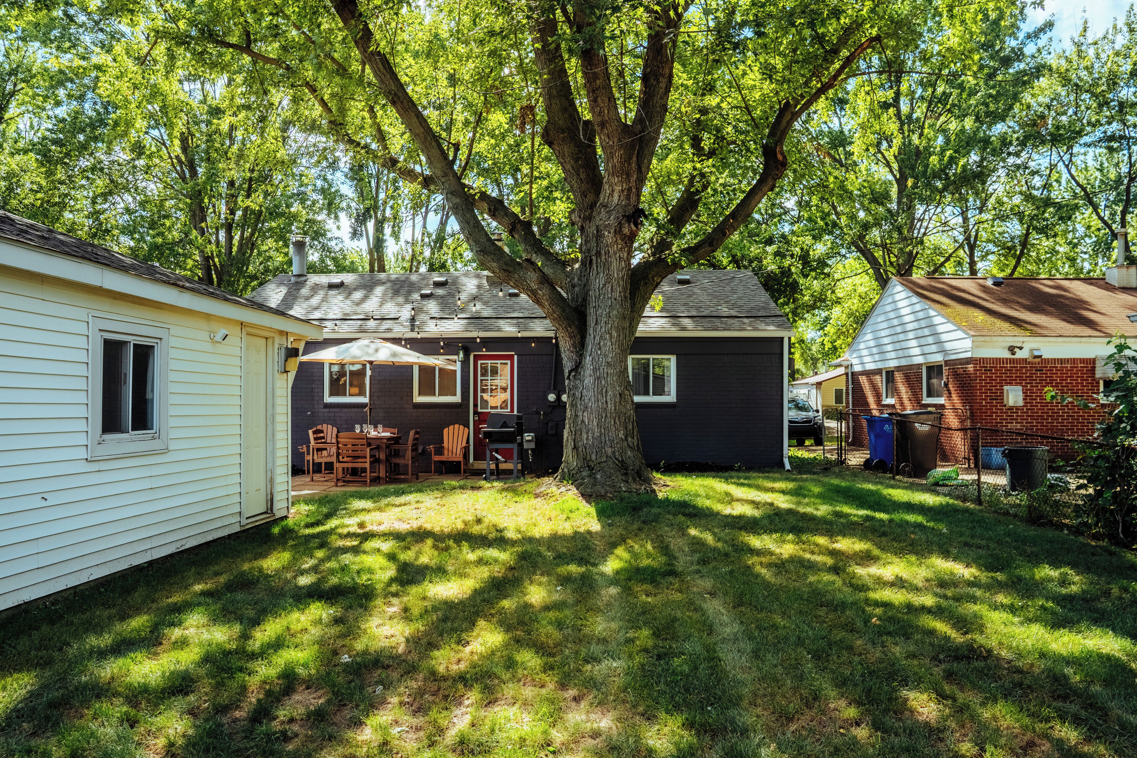 Un quartier résidentiel avec un grand arbre au centre, entouré de maisons aux styles de toiture variés.